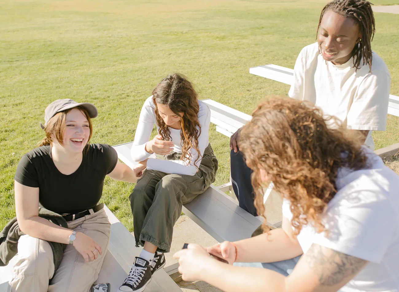 Friends outside on bleachers, laughing.